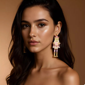 Blush pink nutcracker dangle earrings with gold accents and pearl details.