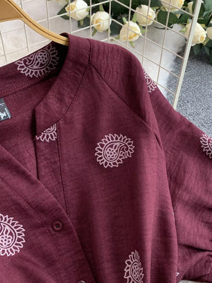 Burgundy jumpsuit with paisley print, V-neck, and button detail.