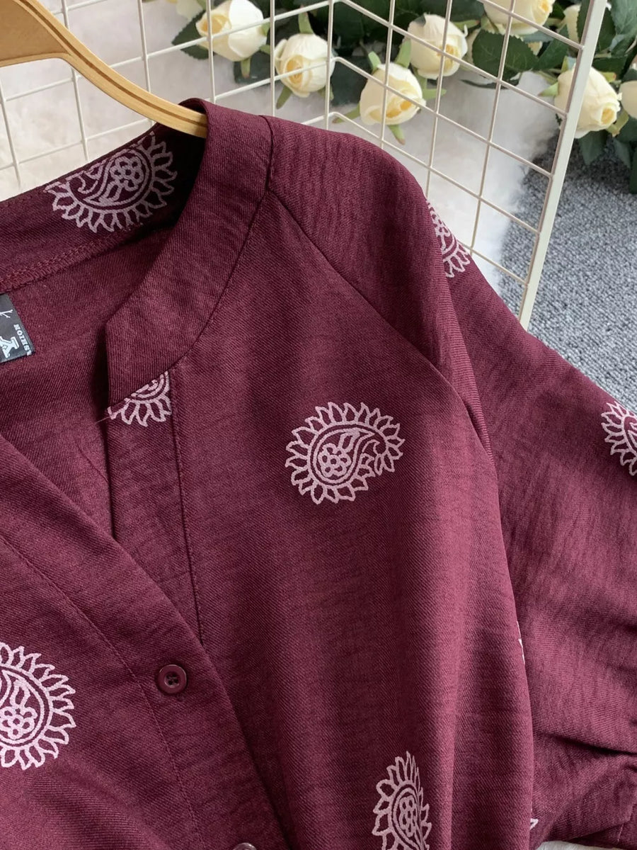 Burgundy jumpsuit with paisley print, V-neck, and button detail.