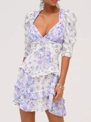 Ruched floral tie-front dress with ruffled tiers and puff sleeves in white with purple and blue flowers.