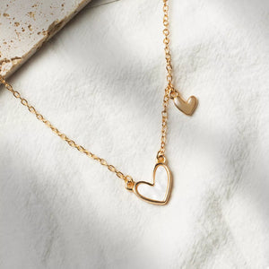 Gold necklace with white heart pendant and small gold heart charm