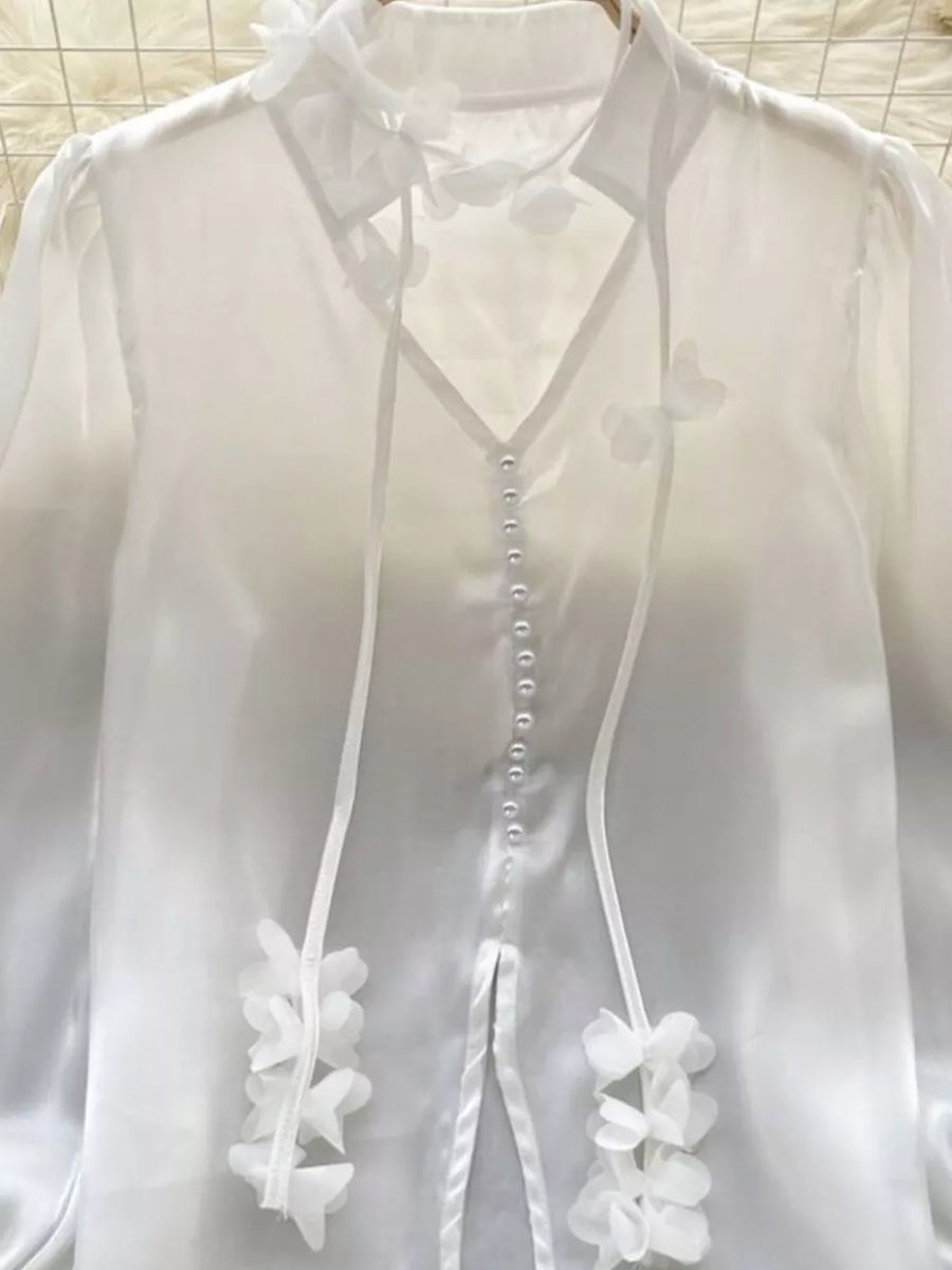 White sheer button-down shirt with delicate floral appliqué and ribbon ties.