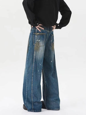 Men's wide-leg jeans in washed blue denim with paint splatter details.
