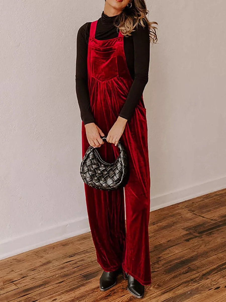 Burgundy velvet wide-leg maternity rompers with a bib front and pockets, styled with a black turtleneck.
