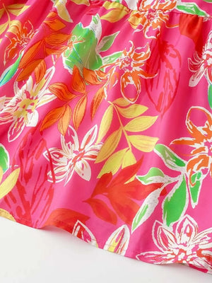 Tropical tie-strap smocked midi dress in strawberry pink with vibrant floral print.
