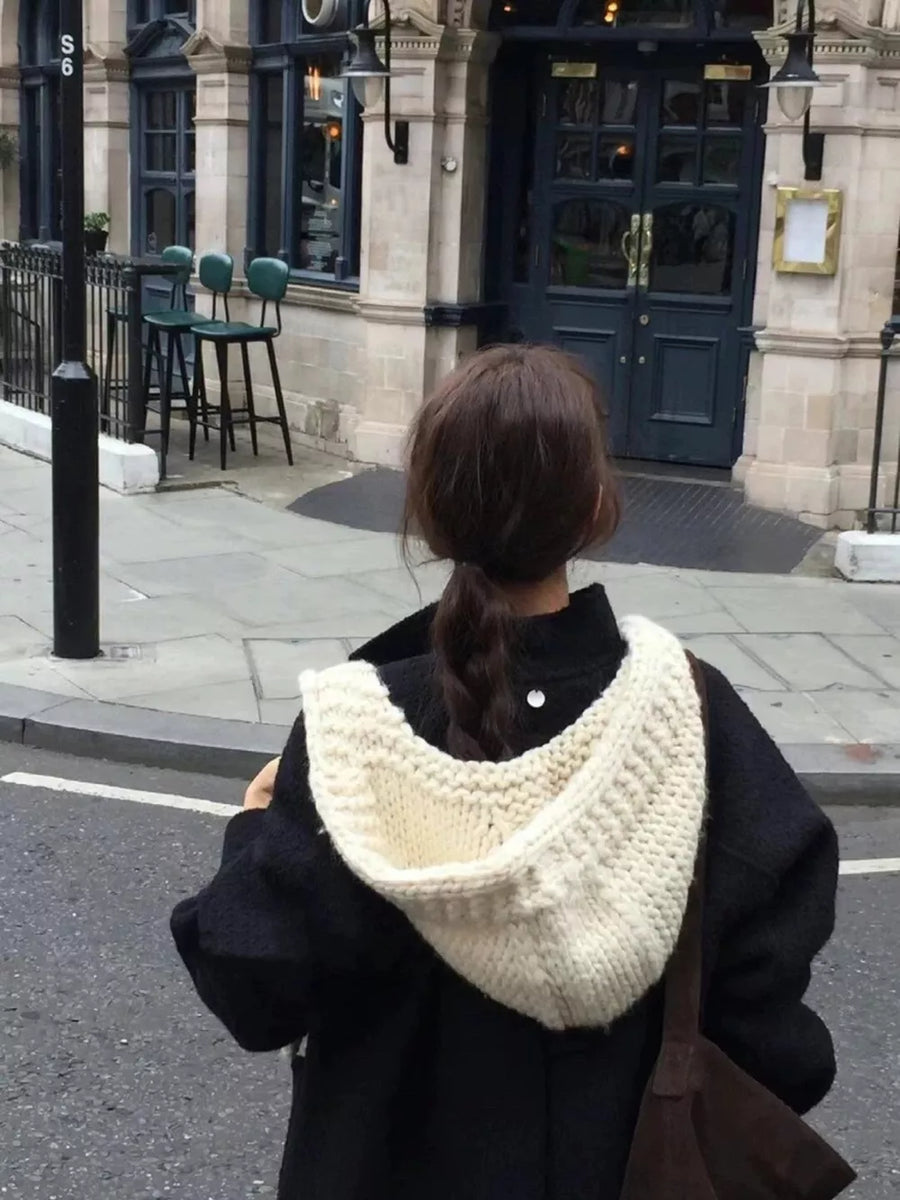 Cozy wool earflap beanie hat in off-white, chunky knit, worn by a person from behind.