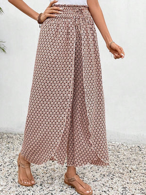 Palazzo pants with a geometric print in blush pink and black, featuring a wrap-front design and smocked waist.