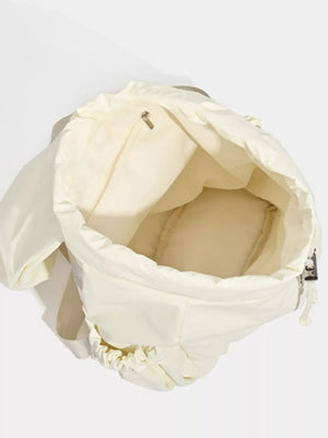 Cream nylon drawstring backpack interior with zip pocket and padded base.
