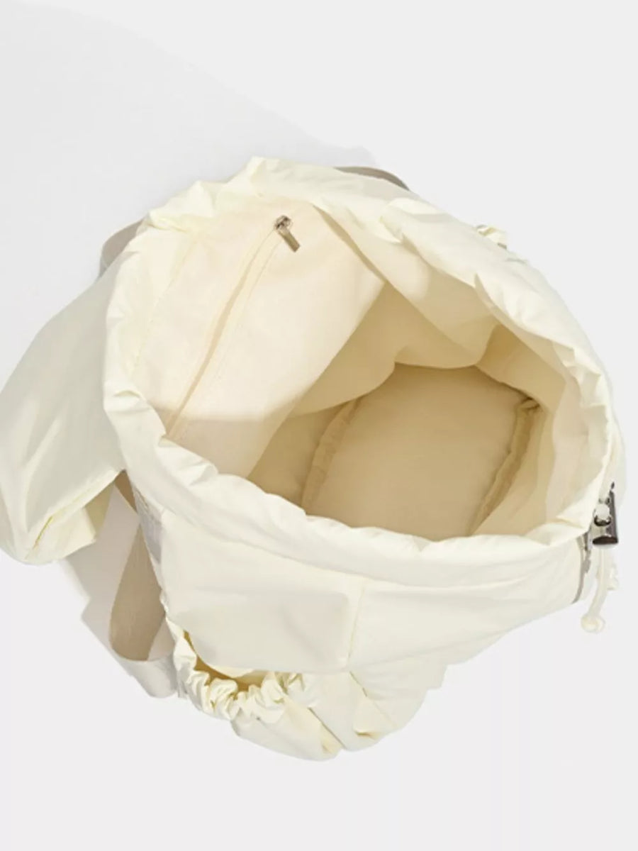 Cream nylon drawstring backpack interior with zip pocket and padded base.