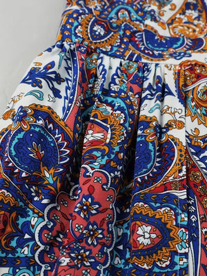 Maternity swim dress with vibrant multicolor paisley print, cinched waist, and dramatic slit detail.