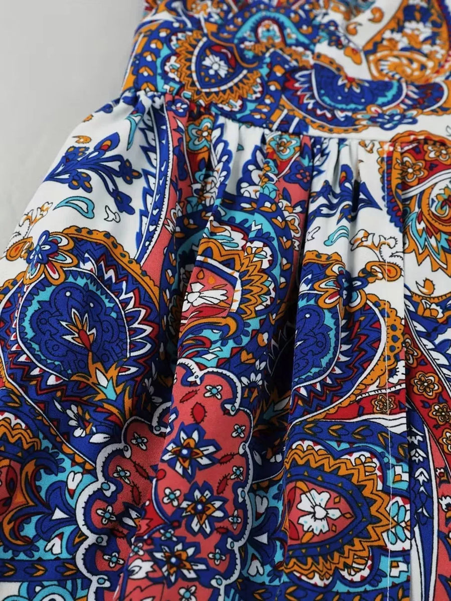 Maternity swim dress with vibrant multicolor paisley print, cinched waist, and dramatic slit detail.
