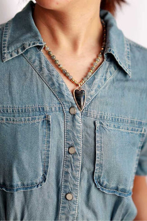Bead pendant necklace with heart-shaped stone on a denim shirt