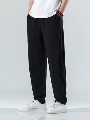 Men's black relaxed fit casual sweatpants with pockets, styled with a white t-shirt and sneakers.