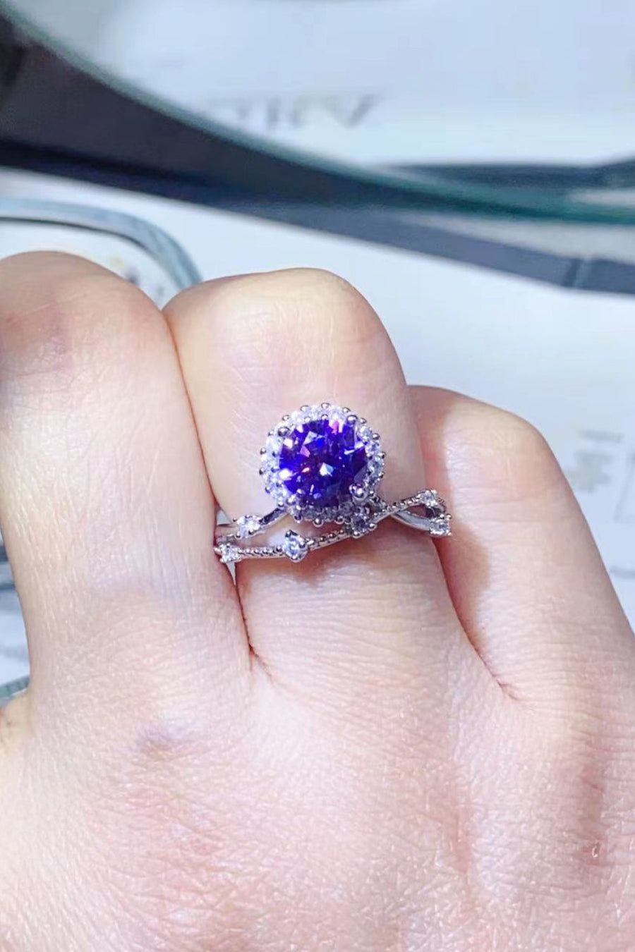 Purple halo moissanite engagement ring set with diamond accents on a twisted band.