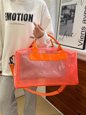 Chic transparent PVC travel bag in orange with mesh detail and leather accents.