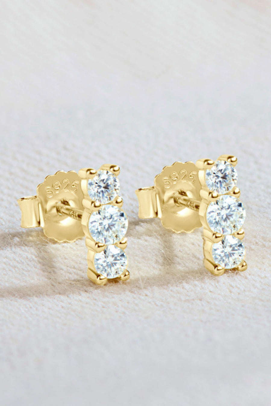 Gold triple stone bar stud earrings with clear cubic zirconia accents.