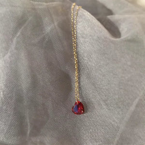 Gold chain necklace with a red heart-shaped zircon pendant.