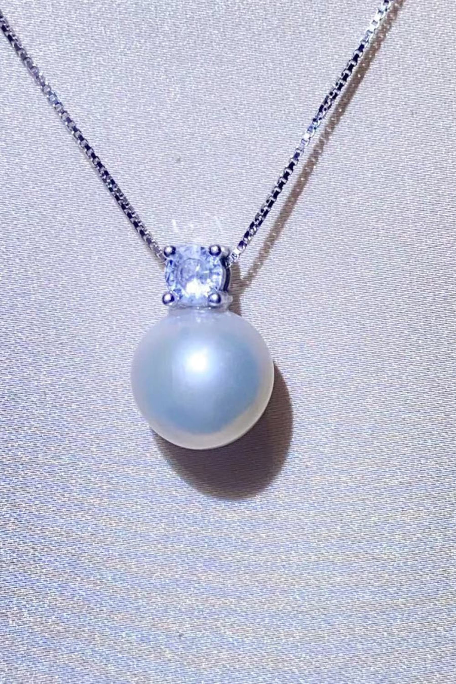 Solitaire pearl pendant necklace in silver with a cubic zirconia accent on a sterling silver chain.