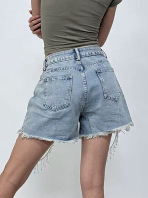 Sky blue denim shorts with rhinestone chain fringe detail and frayed hem.