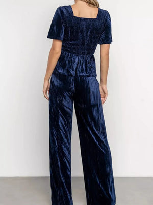 Navy blue velvet two-piece set with flutter sleeves and smocked waist top, wide-leg pants.