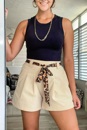 Cream pleated shorts with leopard print tie belt and navy sleeveless top
