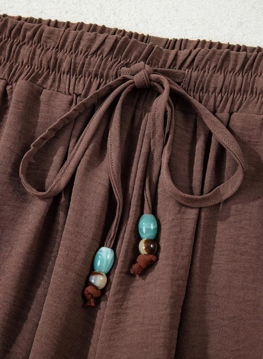 Brown relaxed wide-leg maternity pants with drawstring and beaded detail.
