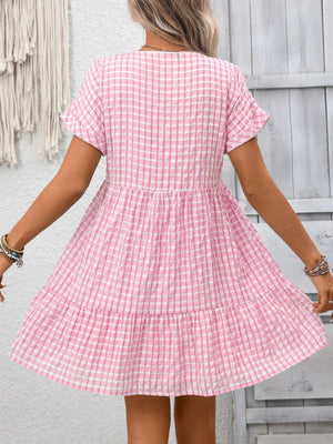 Pink plaid v-neck mini dress with short sleeves and tiered skirt.