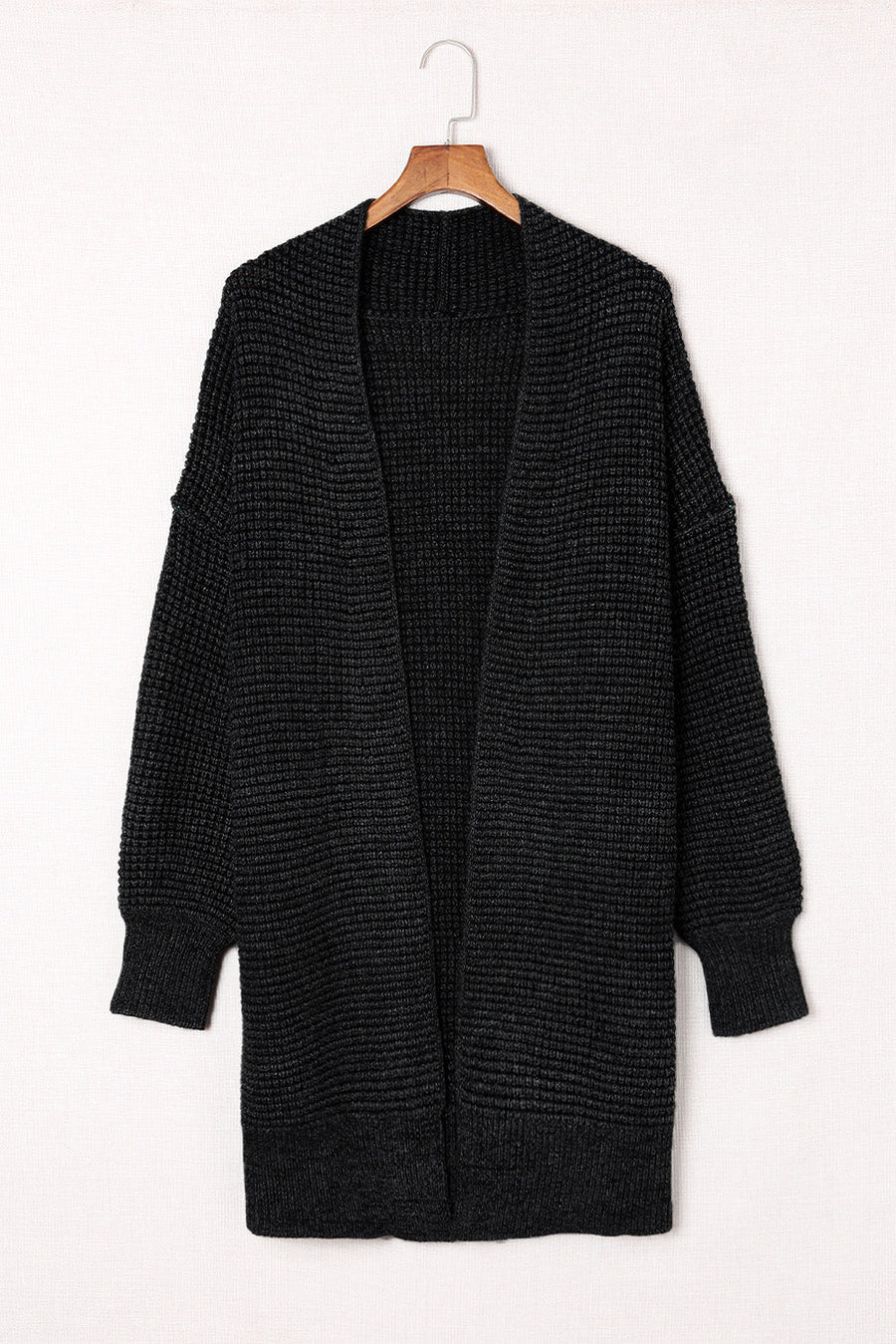 Black textured acrylic open cardigan with puff sleeves and a waffle knit.