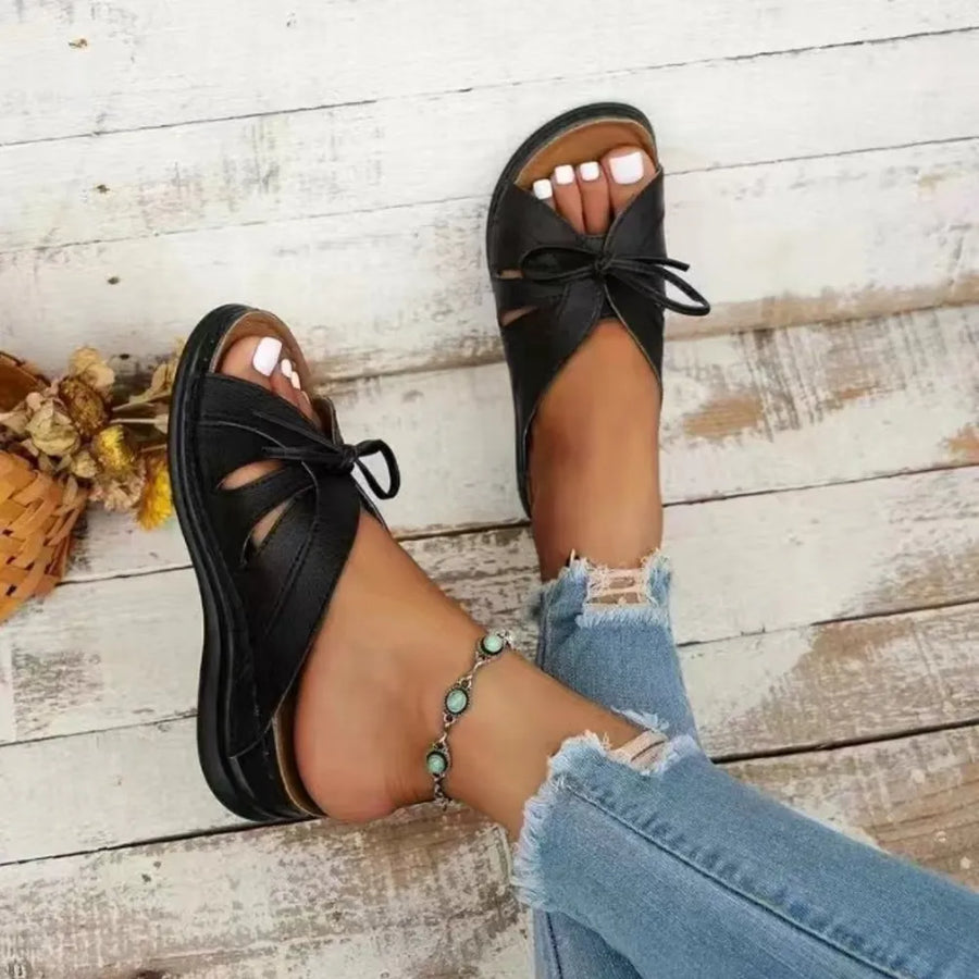 Black leather lace-up cutout slides with bow detail and peep toe.