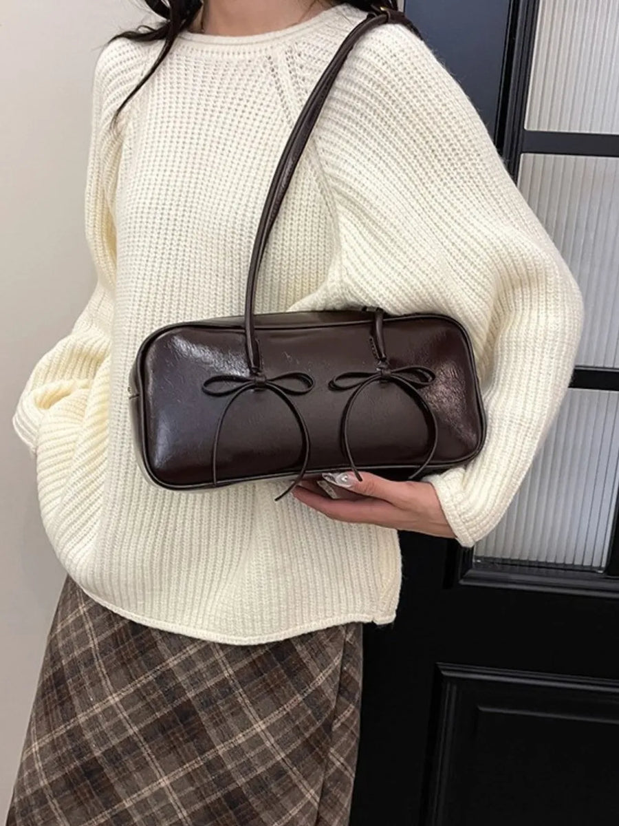 Chocolate patent leather shoulder bag with double bow detail.