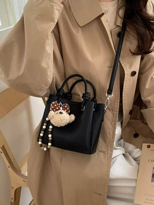 crossbody bag in black featuring top handles and structured fit