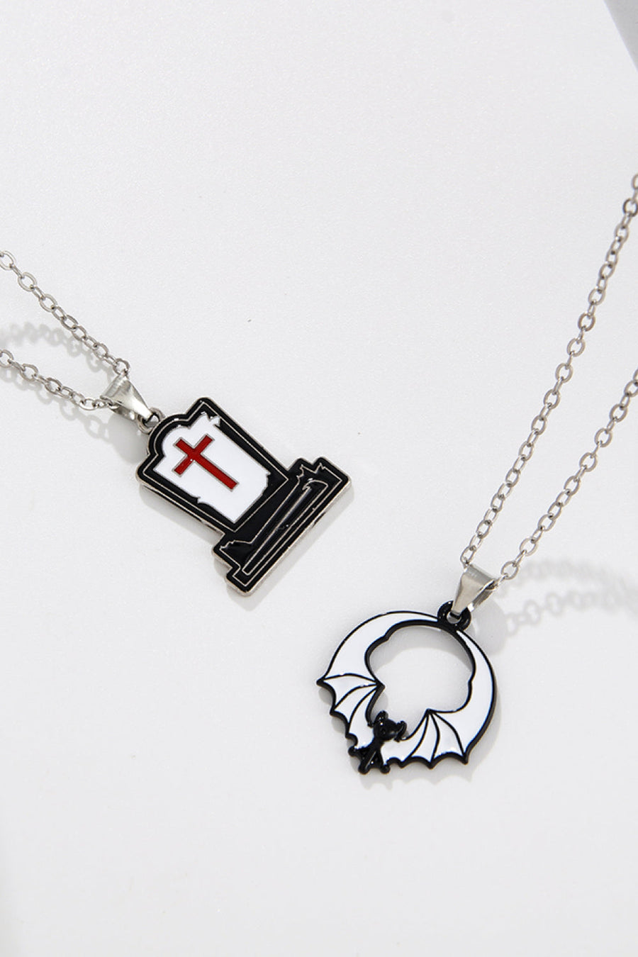 Spooky Season enamel pendant necklaces, one tombstone with red cross, one bat in circle.