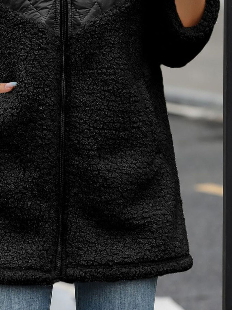 Black teddy hoodie with quilted panel detail and zip closure.