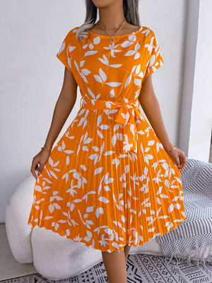 Orange midi dress with white leaf print, short sleeves, belted waist, and pleated skirt.