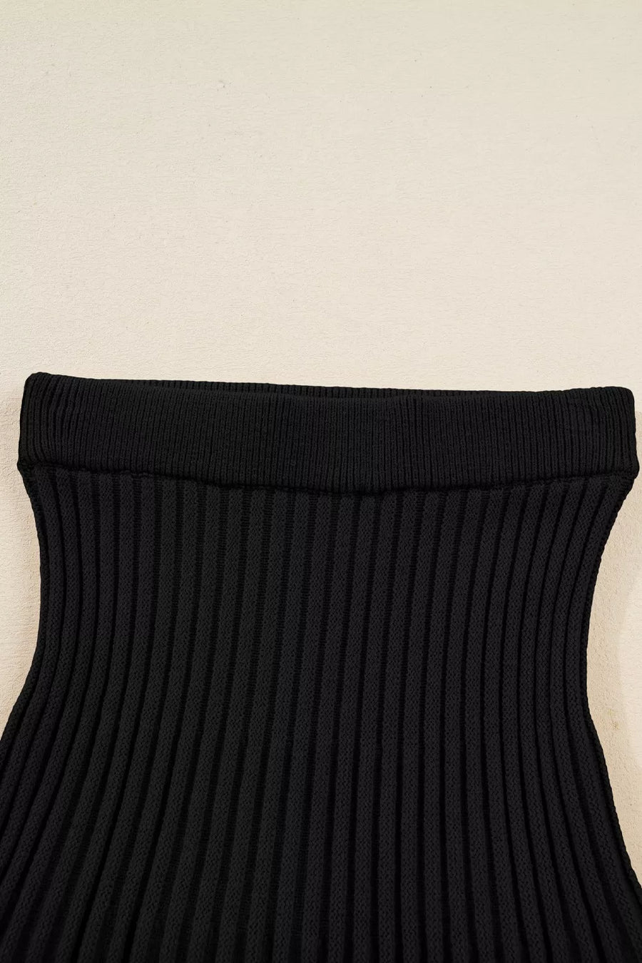 Black ribbed knit pleated skirt with a wide elastic waistband.