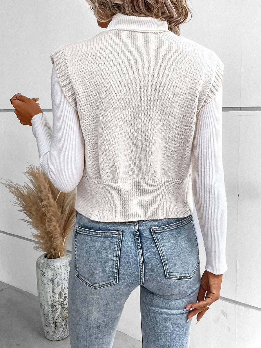 White knit vest with ribbed trim and button detail, worn over a turtleneck.