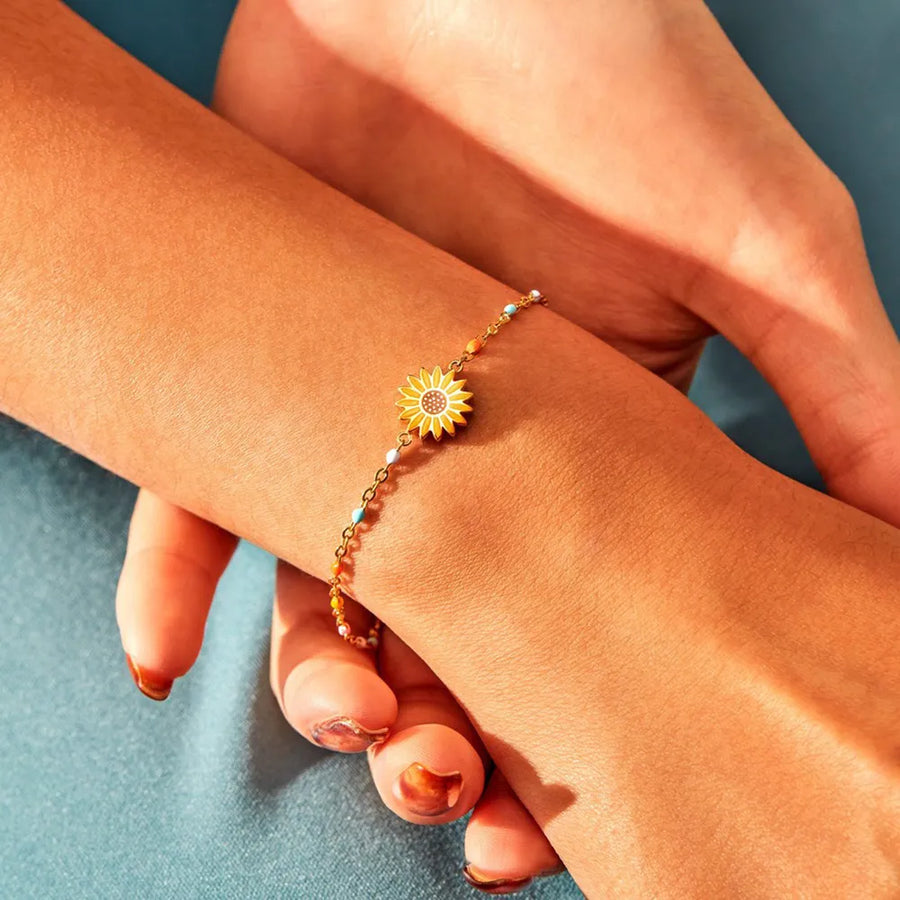 Gold beaded bracelet with a yellow sunflower charm and colorful accent beads.
