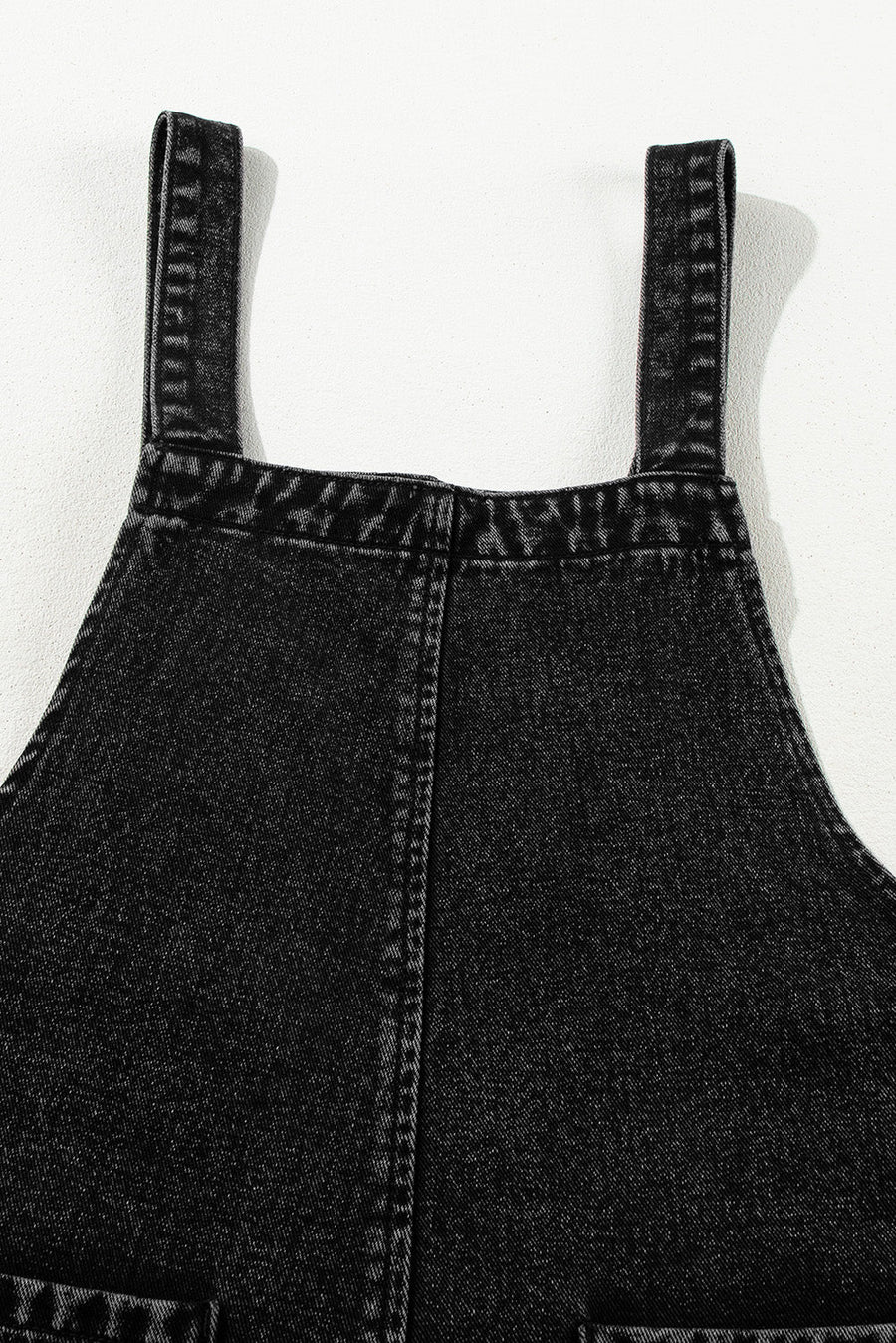 Black denim culotte overalls with distressed details and adjustable straps.