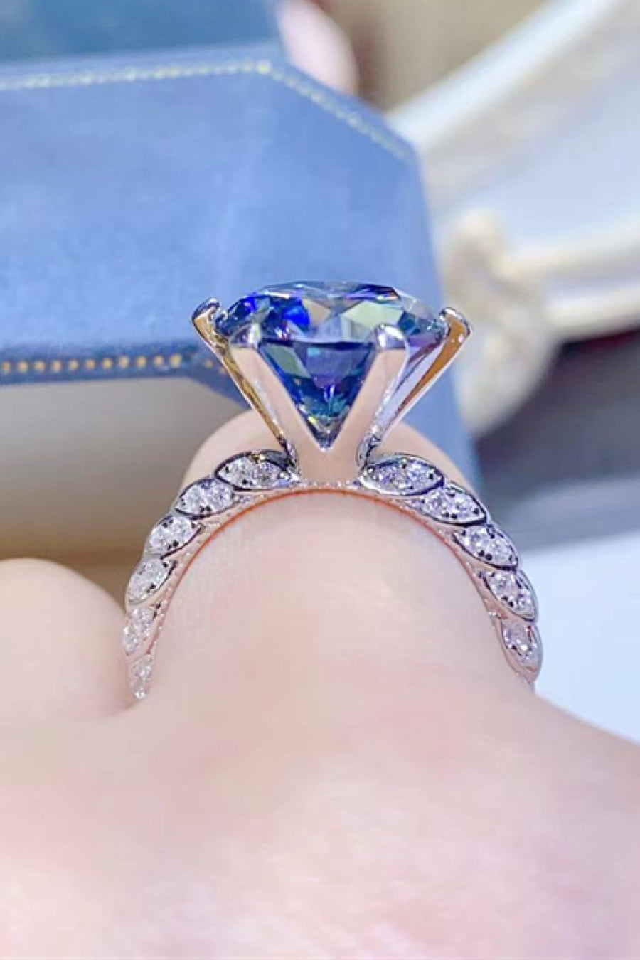 Midnight blue solitaire engagement ring with pavé diamond band.