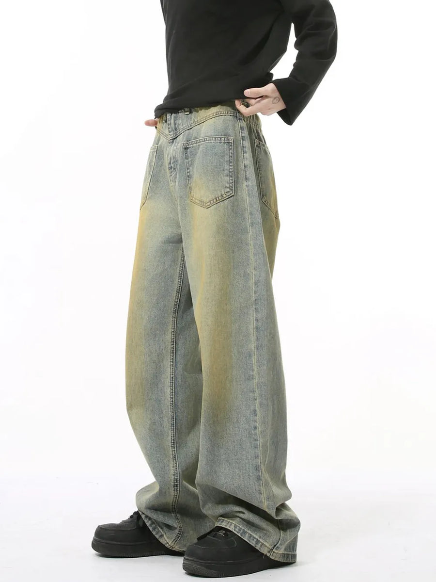 Distressed denim jeans in a medium wash with a relaxed fit and yellowed accents.