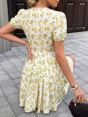 White floral print dress with short puff sleeves and a pleated skirt.