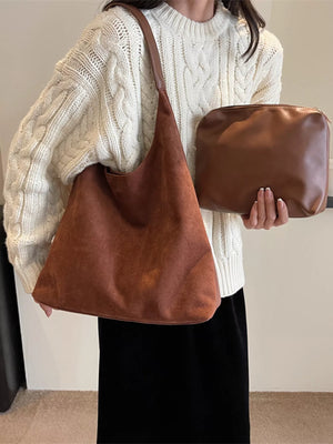 Brown suede shoulder bag with matching pouch, worn with a cream cable knit sweater.