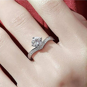 Sterling silver ring with a large center moissanite and small accent stones on a V-shaped band.
