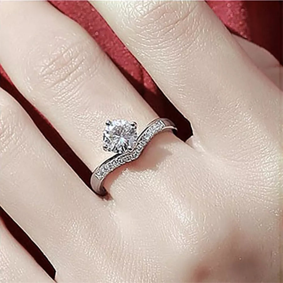Sterling silver ring with a large center moissanite and small accent stones on a V-shaped band.
