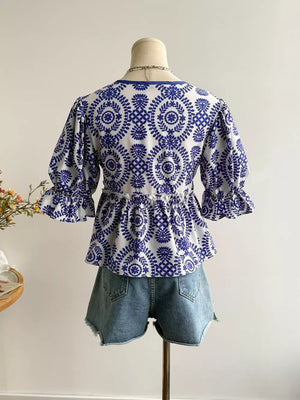 Chic floral blouse with 3/4 ruffled sleeves and tie-front detail, paired with denim shorts.
