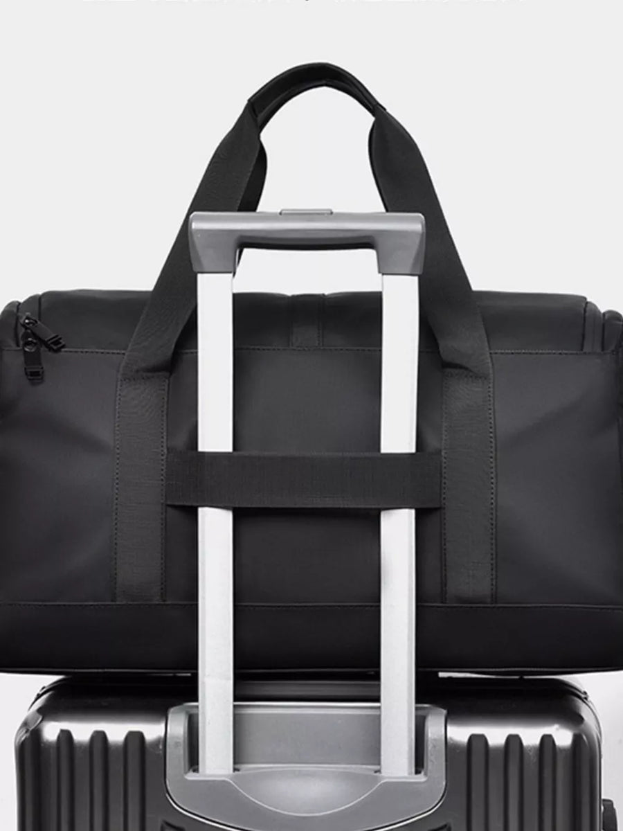 Black Oxford cloth travel bag with top handles and a luggage strap detail.