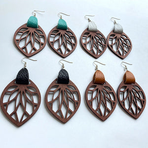 Leaf cutout wood dangle earrings with leather accents in teal, white, black, and caramel.
