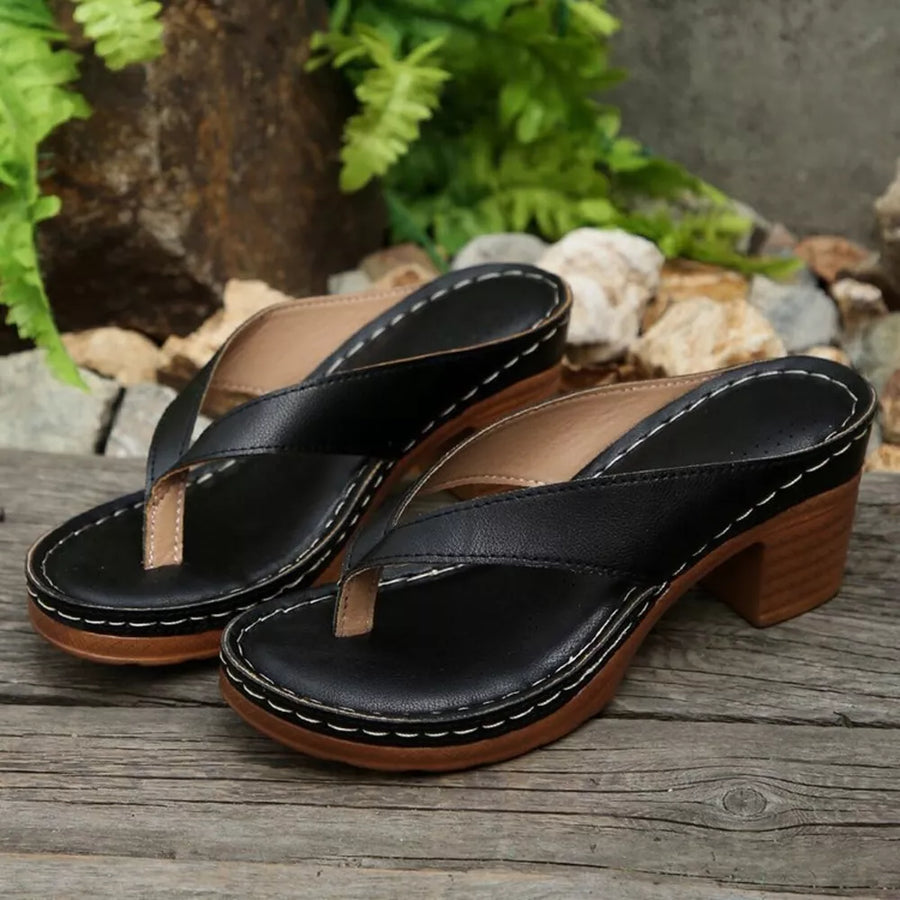 Black toe-post block heel sandals with white stitching and wooden heel.