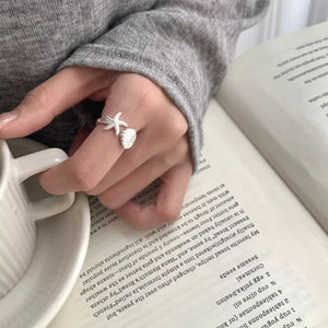 Silver ring featuring open ring and starfish and seashell motif