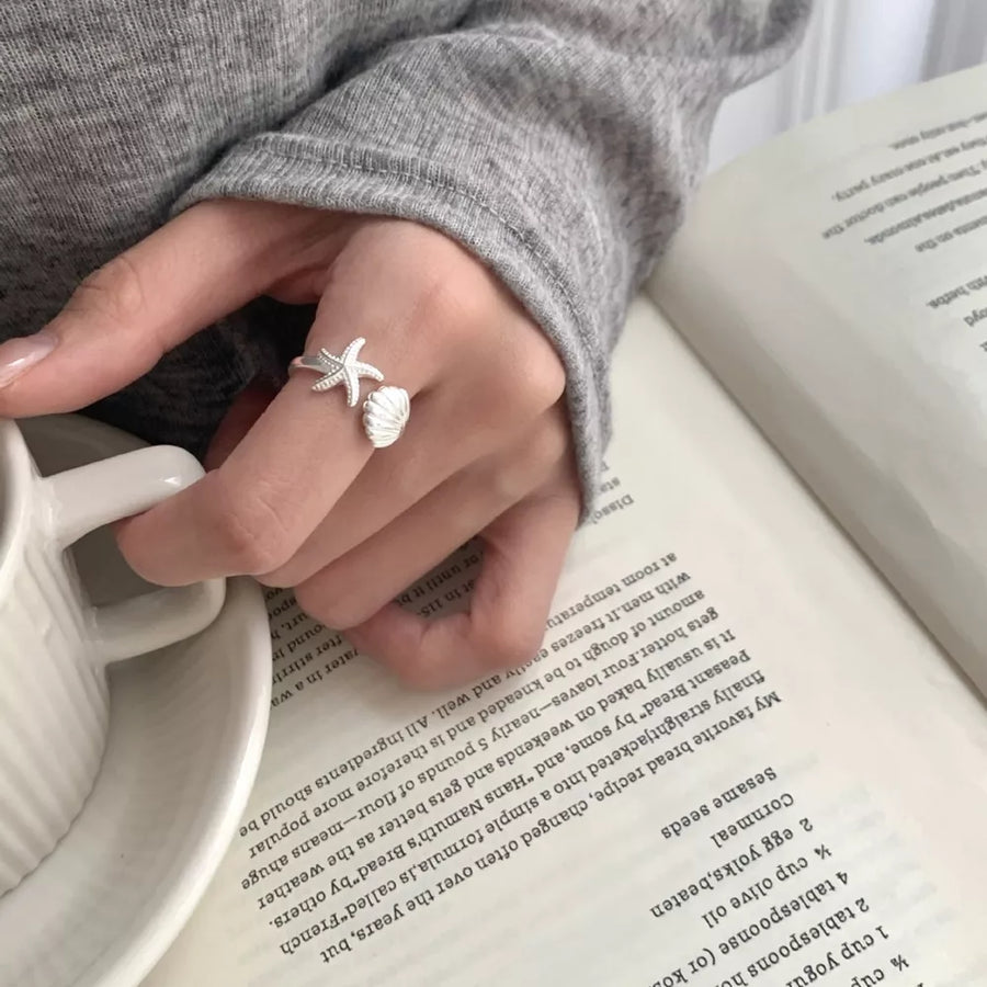 Silver ring featuring open ring and starfish and seashell motif